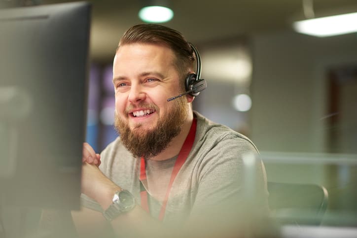 IT Support Liquid Web - man on headset ready to talk to customer at his workstation.