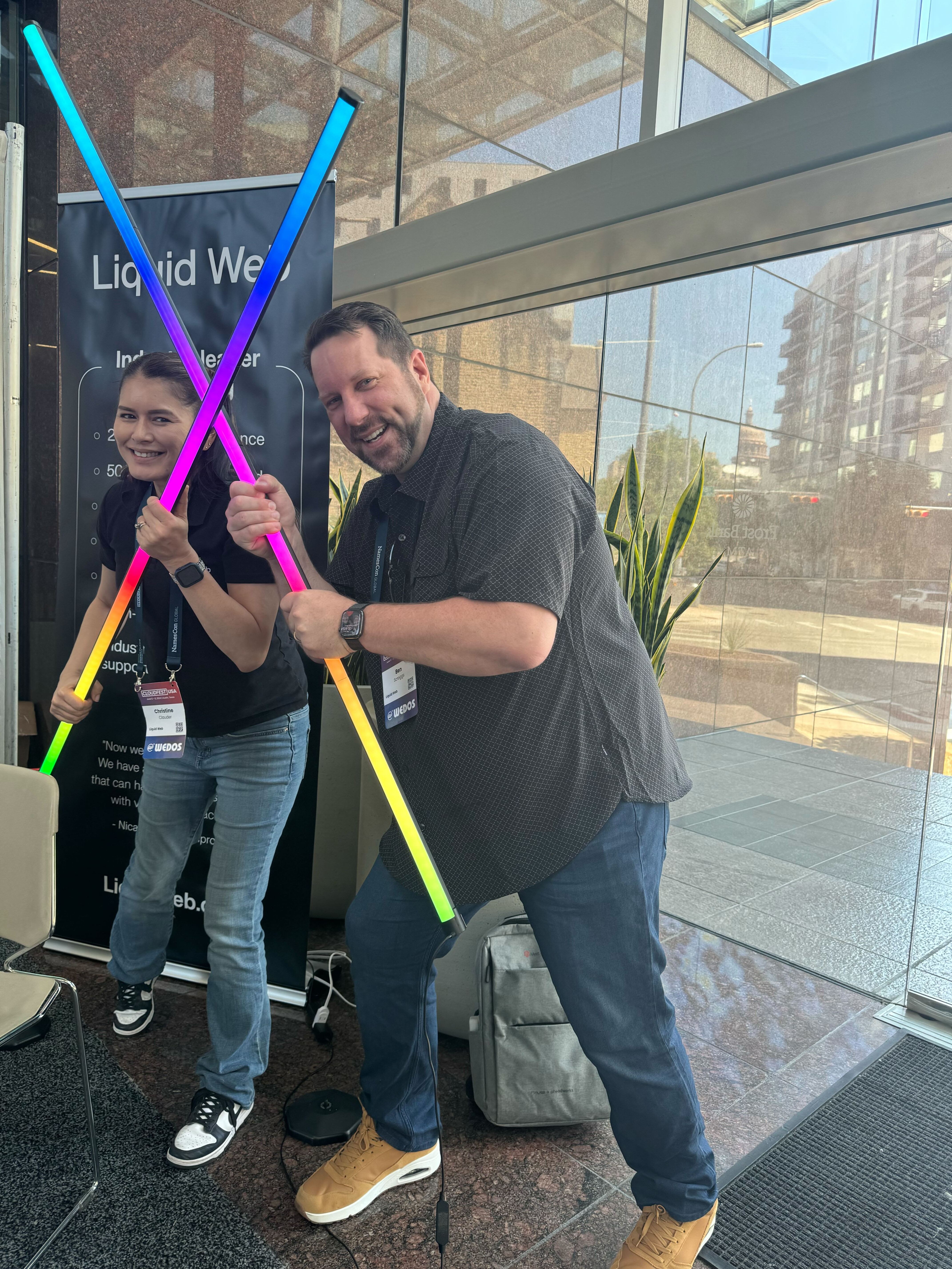 Two members of the Liquid Web field team posing with rainbow lights in front of their booth