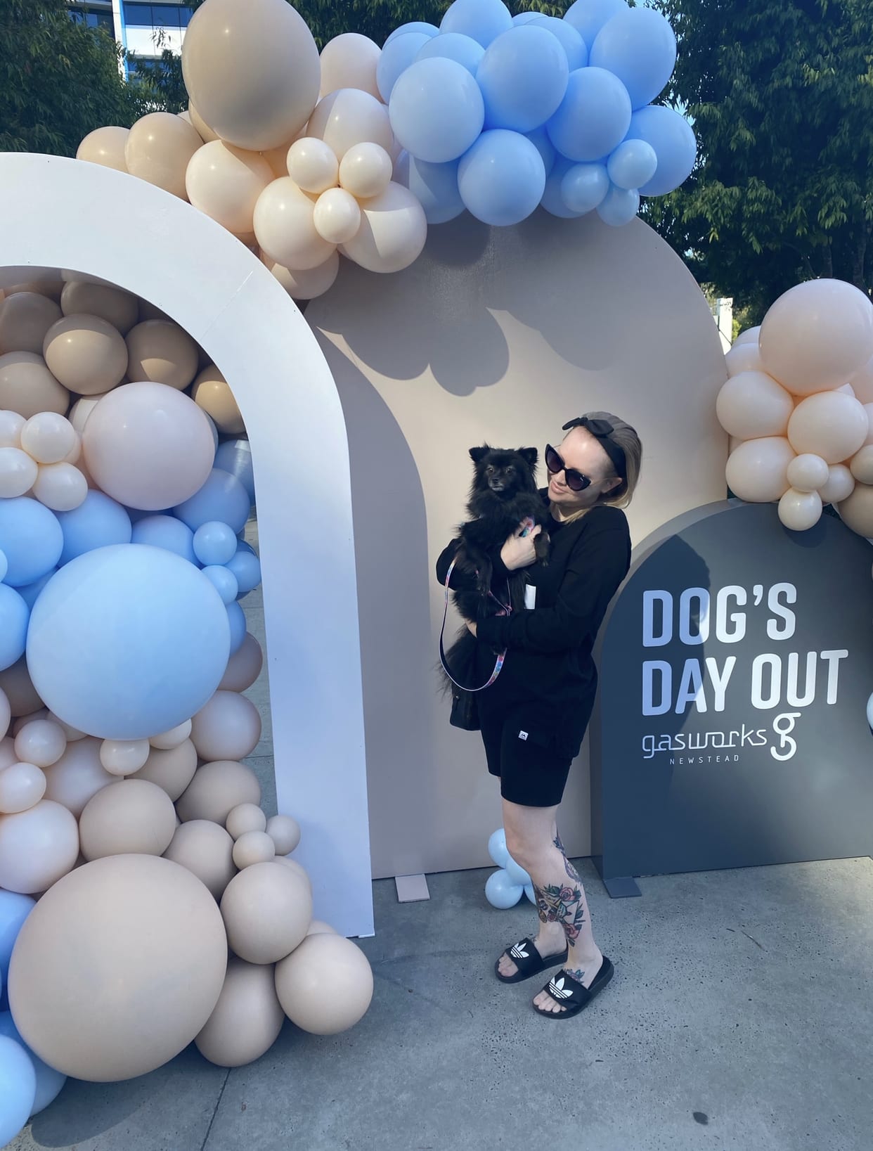 Woman and black Pomeranian posing in front of balloons