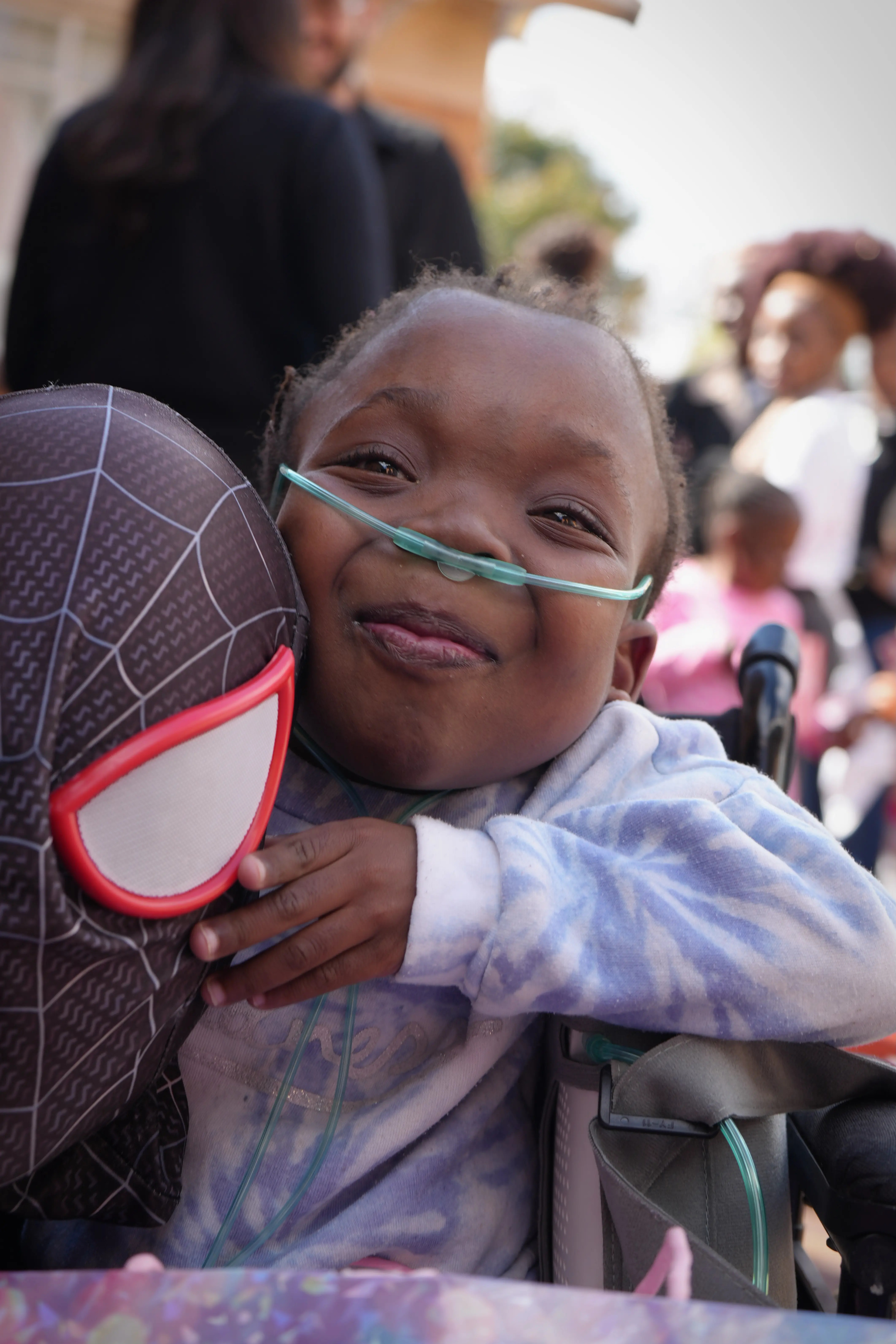 A child at Marang House smiling while hugging a toy