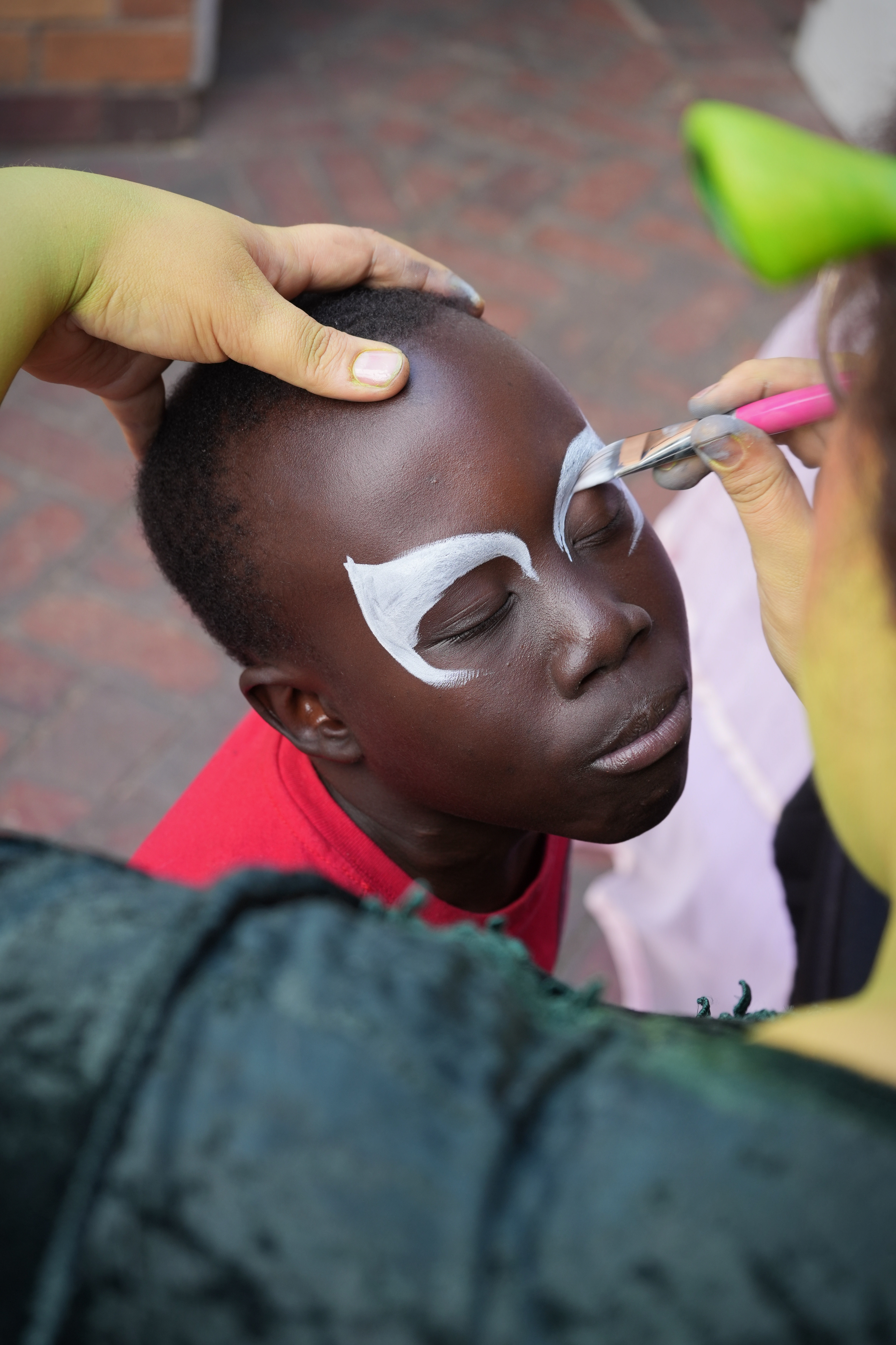 A child with colourful face paint at Marang House Garden Day