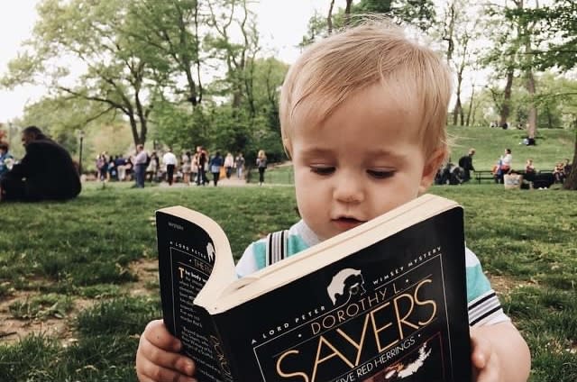 A toddler absorbed in reading a Dorothy L. Sayers mystery in the park