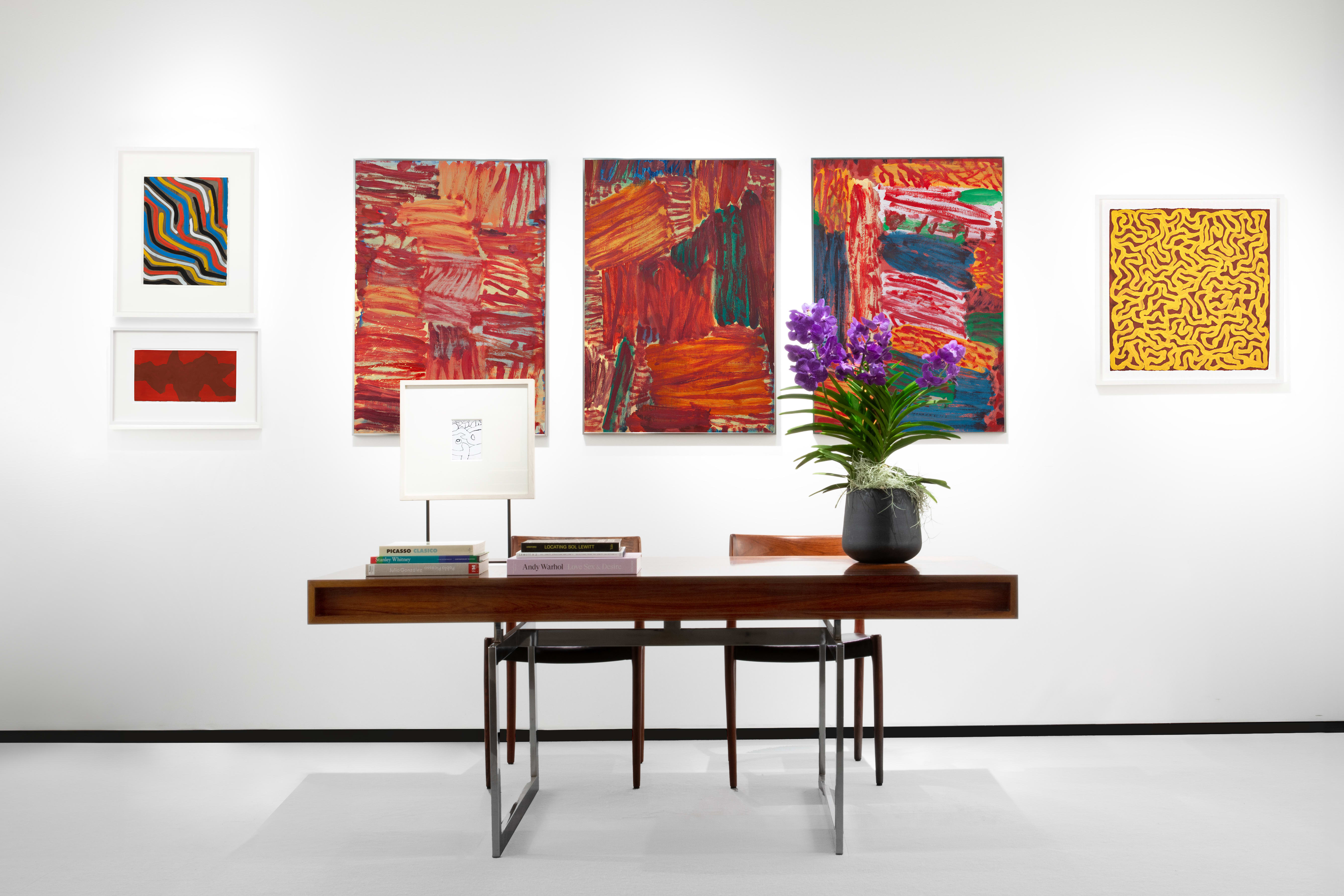 Installation view at Salon du dessin 2024 in Paris, with framed works arranged in a horizontal line on a white booth wall above a seating area.