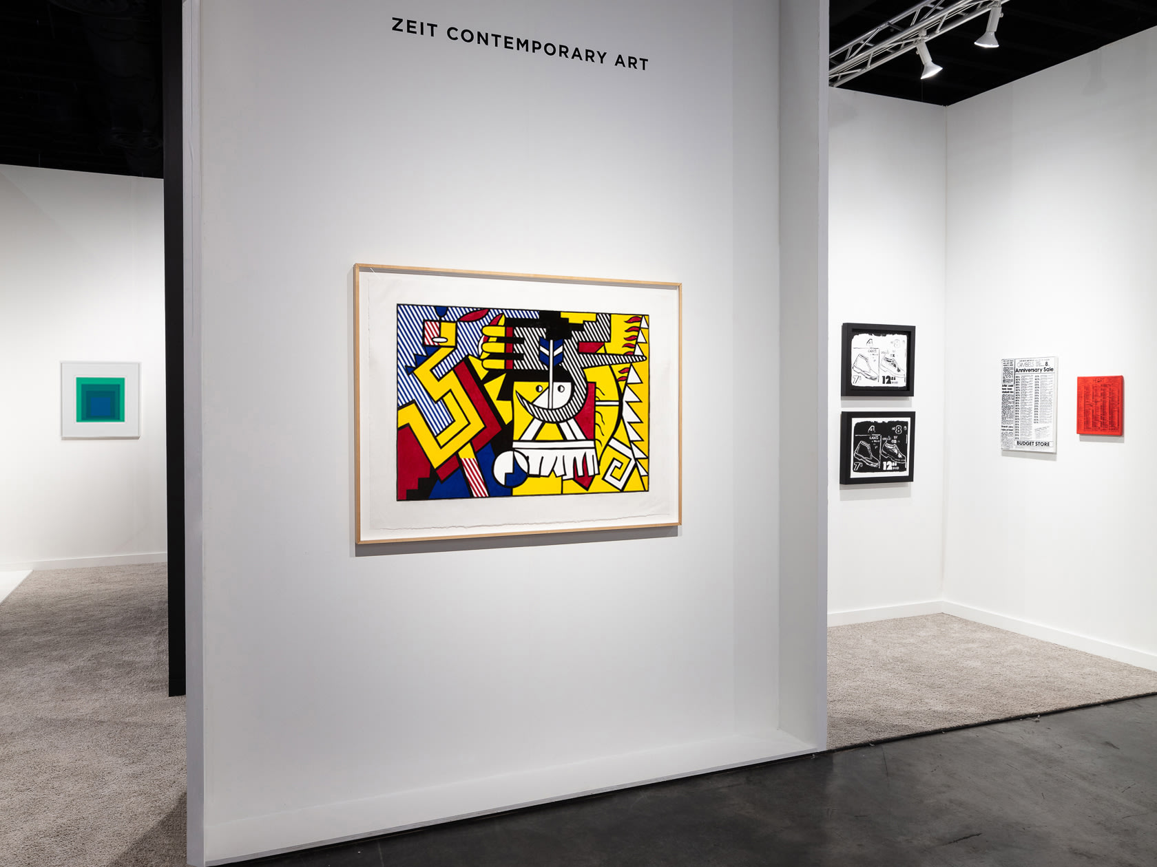 Installation view at Palm Beach Modern + Contemporary 2022 in West Palm Beach, showing framed works across multiple white wall planes in an angled view into the booth.