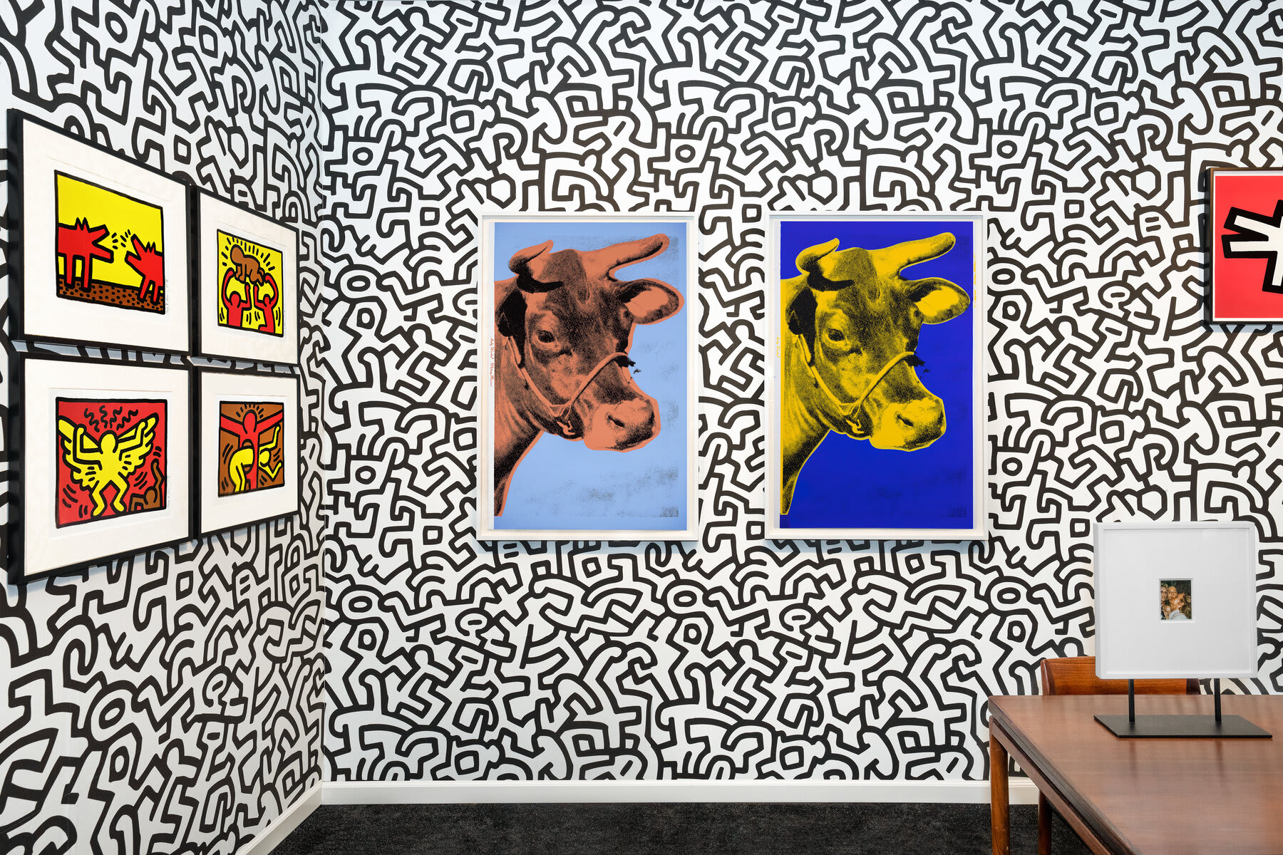 Installation view at Hamptons Fine Art Fair 2022 in Southampton, with framed works across two corner walls and the edge of a table visible below.