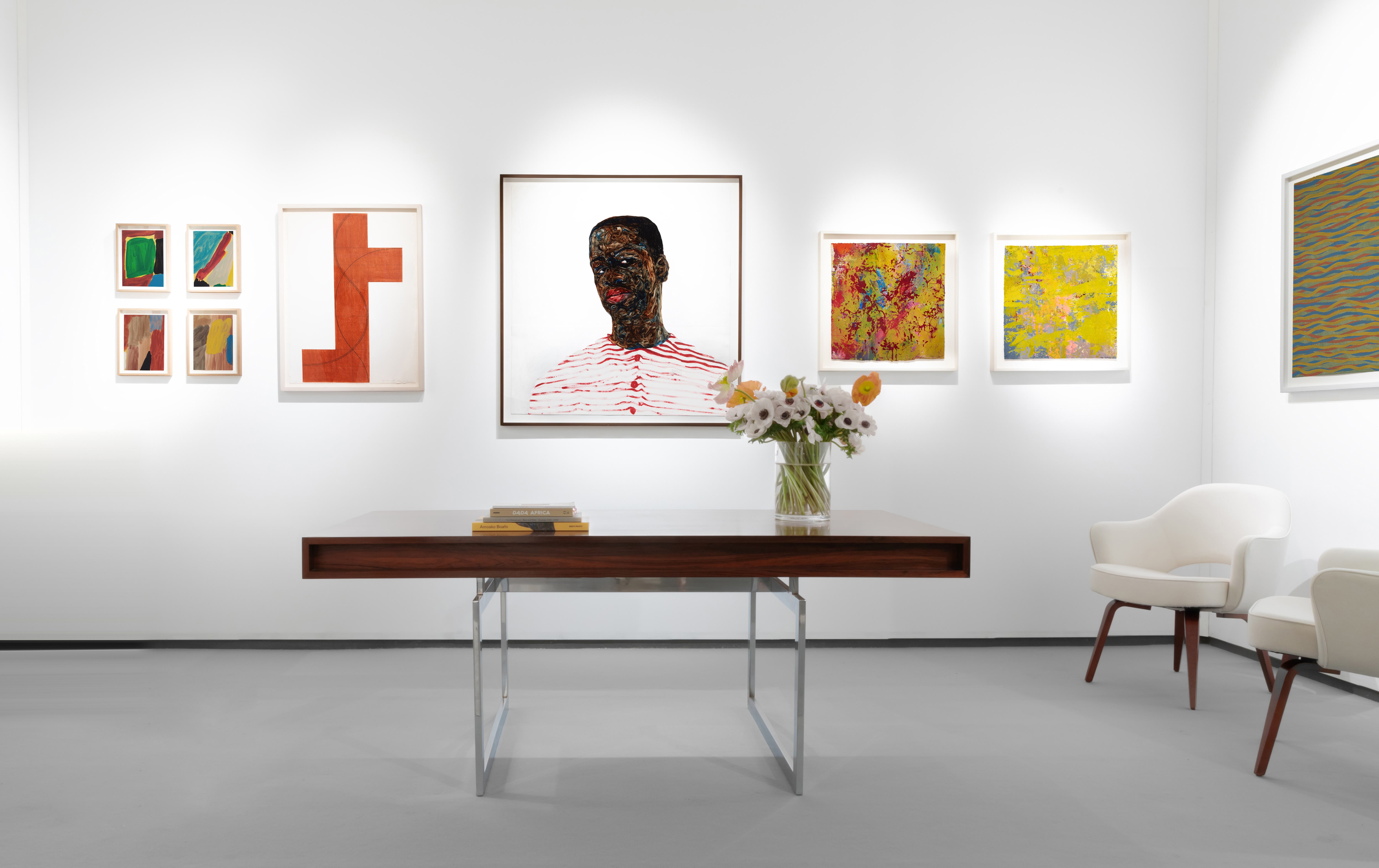 Installation view at Salon du dessin 2023 in Paris, with framed works arranged in a horizontal line on a white booth wall above a seating area.