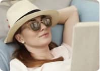 Woman in hat and sunglasses reading