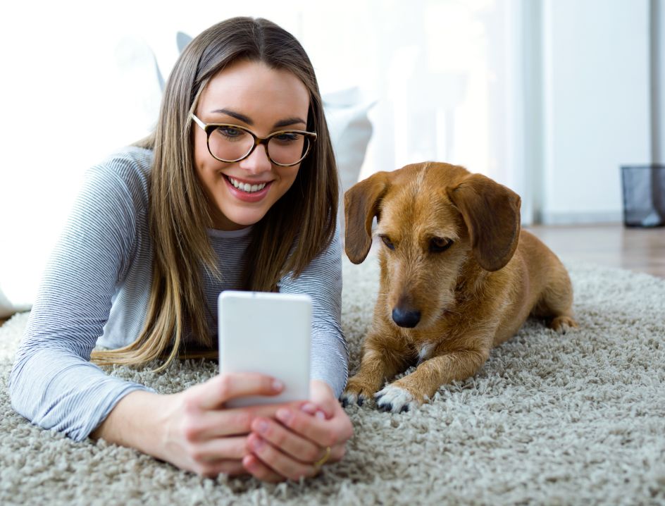 Woman holds a phone on the floor with dog