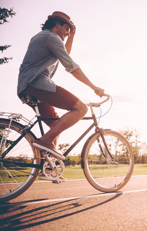 Two people ride bikes with the sun out