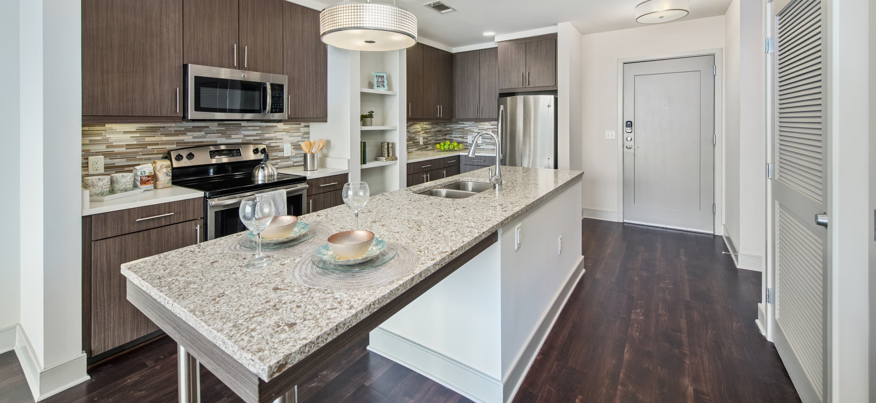 Front view of modern-style kitchen with stainless steel appliances, kitchen island with sink and granite countertops at MAA Lenox luxury apartments in Atlanta, GA