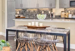 Dining table and modern clear chairs next to kitchen bar top counter at MAA Centennial Park luxury apartments in Atlanta, GA