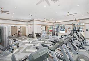 Open room view of fitness center with treadmills and weight machines at MAA West Village luxury apartments in Smyrna, GA