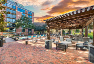 Poolside seating area with a pergola on a brick patio at MAA Heights luxury apartments in Dallas, TX