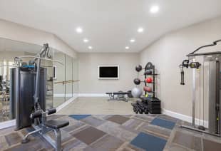 Fitness center studio space with mirrored walls and exercise equipment racks at MAA Shiloh luxury apartments in Kennesaw, GA