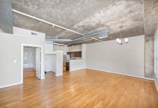 Open space empty living room area next to kitchen with wood flooring at MAA Addison Circle luxury apartments in Addison, TX