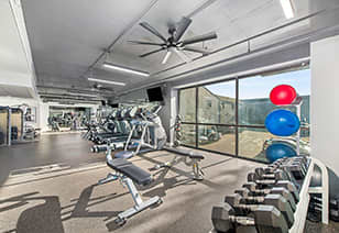 An organized fitness center filled with weights and diverse exercise equipment at MAA Gallery luxury apartments in Dallas, TX