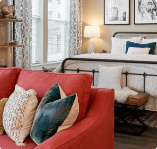 Model studio with full-size bed and a red couch at MAA Centennial Park luxury apartments in Atlanta, GA
