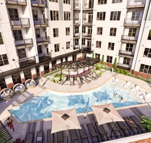 Upscale rooftop resort-style saltwater pool at MAA Plaza Midwood luxury apartments for rent in Charlotte, NC, featuring modern cabanas and grilling area for outdoor entertaining