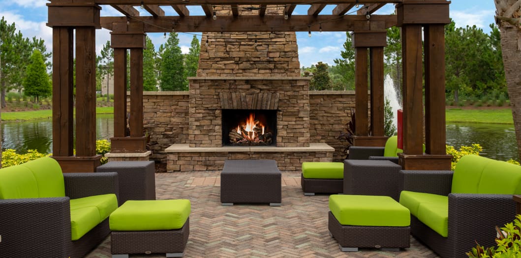 Outdoor fireplace by Pond at Colonial Grand Apartments at Hampton Preserve luxury apartment homes in Tampa, FL