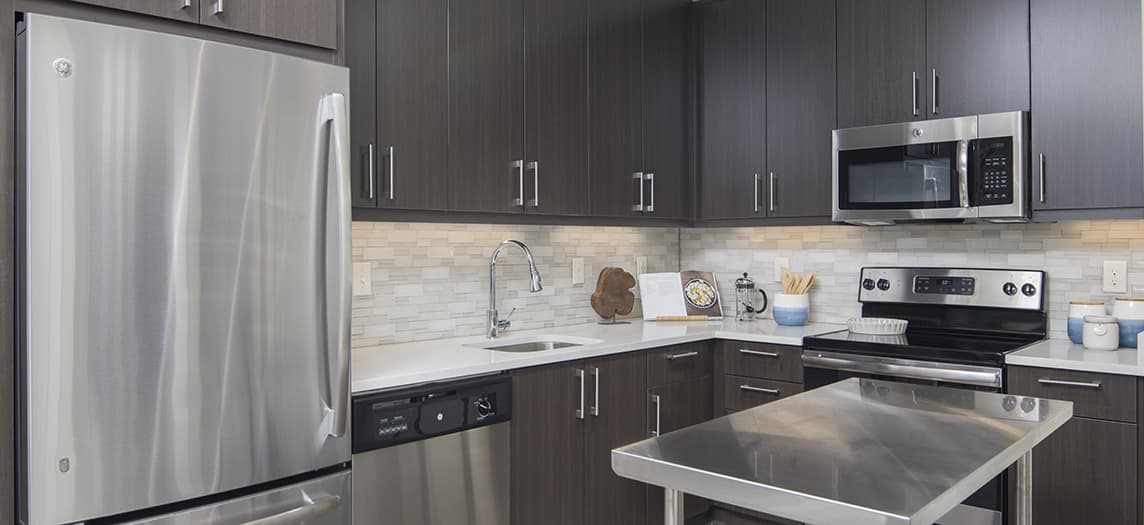 Kitchen with brown cabinets and stainless steel appliances at MAA Centennial Park luxury apartments in Atlanta, GA