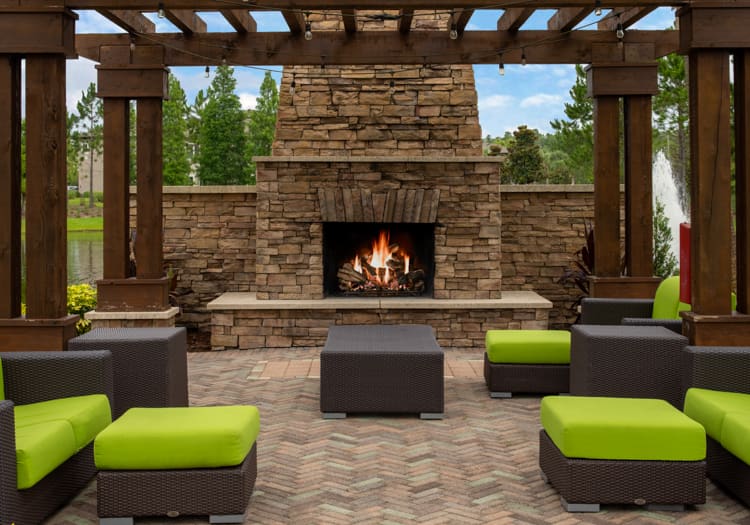 Outdoor fireplace by Pond at Colonial Grand Apartments at Hampton Preserve luxury apartment homes in Tampa, FL