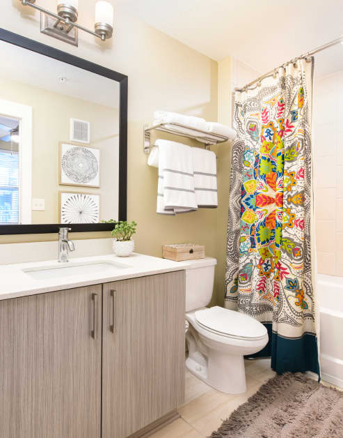 Bathroom sink with vanity and light cabinets with a colorful shower curtain at MAA Centennial Park luxury apartments in Atlanta, GA