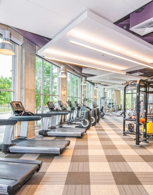 Fitness center with treadmills next to large windows at MAA Centennial Park luxury apartments in Atlanta, GA