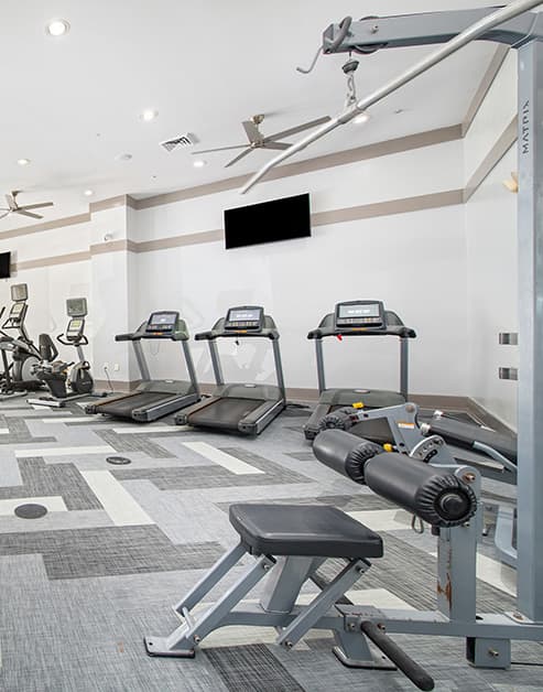 Fitness center with treadmills and wall mounted TV at MAA West Village luxury apartments in Smyrna, GA