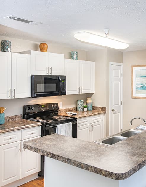 Spacious corner kitchen with white cabinets and bar top counter at MAA Berkeley Lake luxury apartments in Duluth, GA