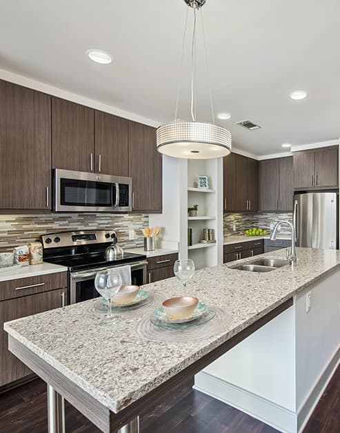 Front view of modern-style kitchen with stainless steel appliances, kitchen island with sink and granite countertops at MAA Lenox luxury apartments in Atlanta, GA