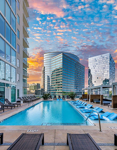 Outward view of rooftop wading pool with sun shelf surrounded by cabana-style lounging area at MAA Lenox luxury apartment homes in Atlanta, GA