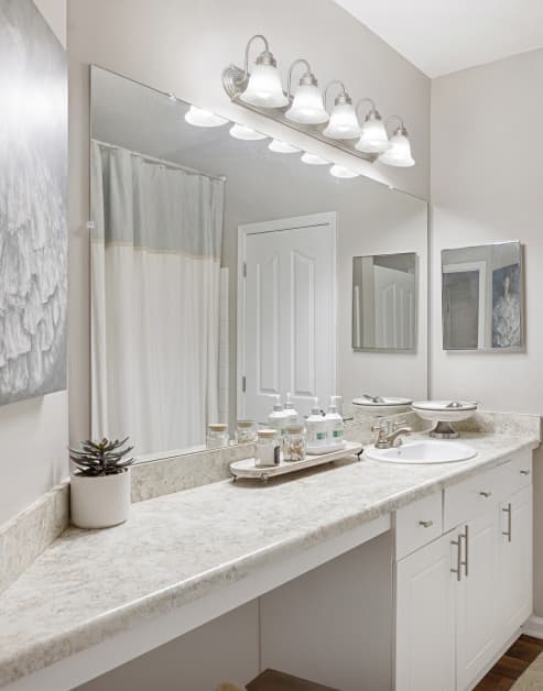 Modern bathroom with bright lighting above large vanity mirror and single sink at MAA Shiloh luxury apartments in Kennesaw, GA