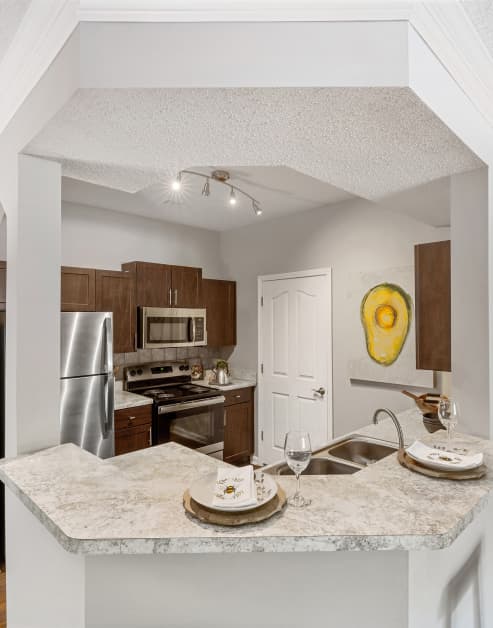 Modern kitchen with brown cabinets and upgraded appliances at MAA Shiloh luxury apartments in Kennesaw, GA