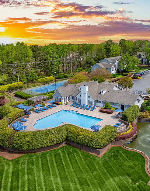 Aerial view of pool area with lounge chairs, sun umbrella with table and chairs next to clubhouse at MAA Fifty-One luxury apartments in Matthews, NC
