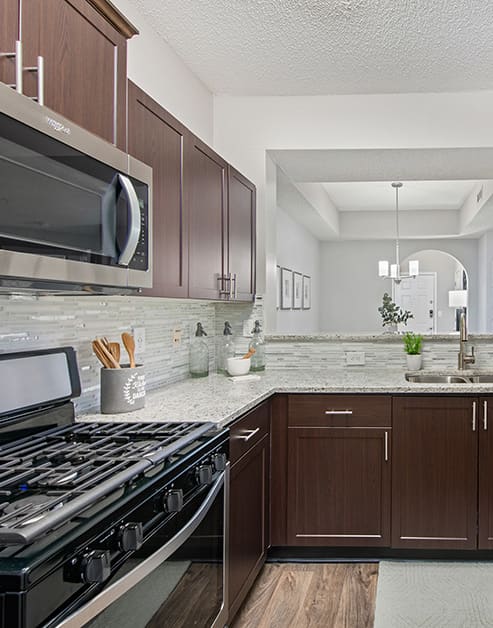 Upscale kitchen with dark brown cabinets, granite counter top, modern appliances and wood floors at MAA South Park luxury apartments in Charlotte, NC