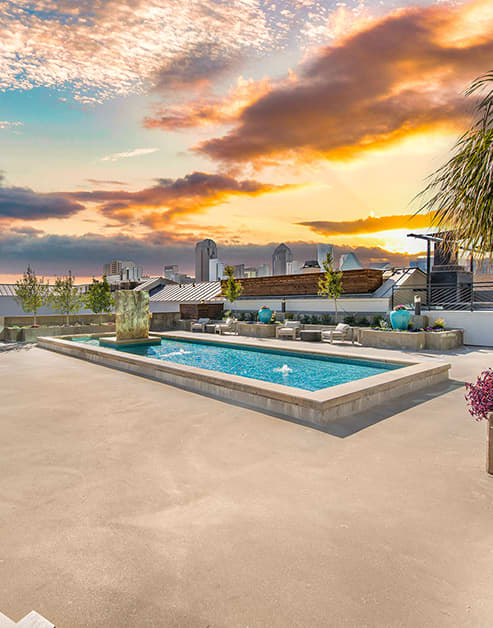 A view of the rooftop reflecting pool next to sitting lounge areas at MAA Gallery luxury apartments in Dallas, TX