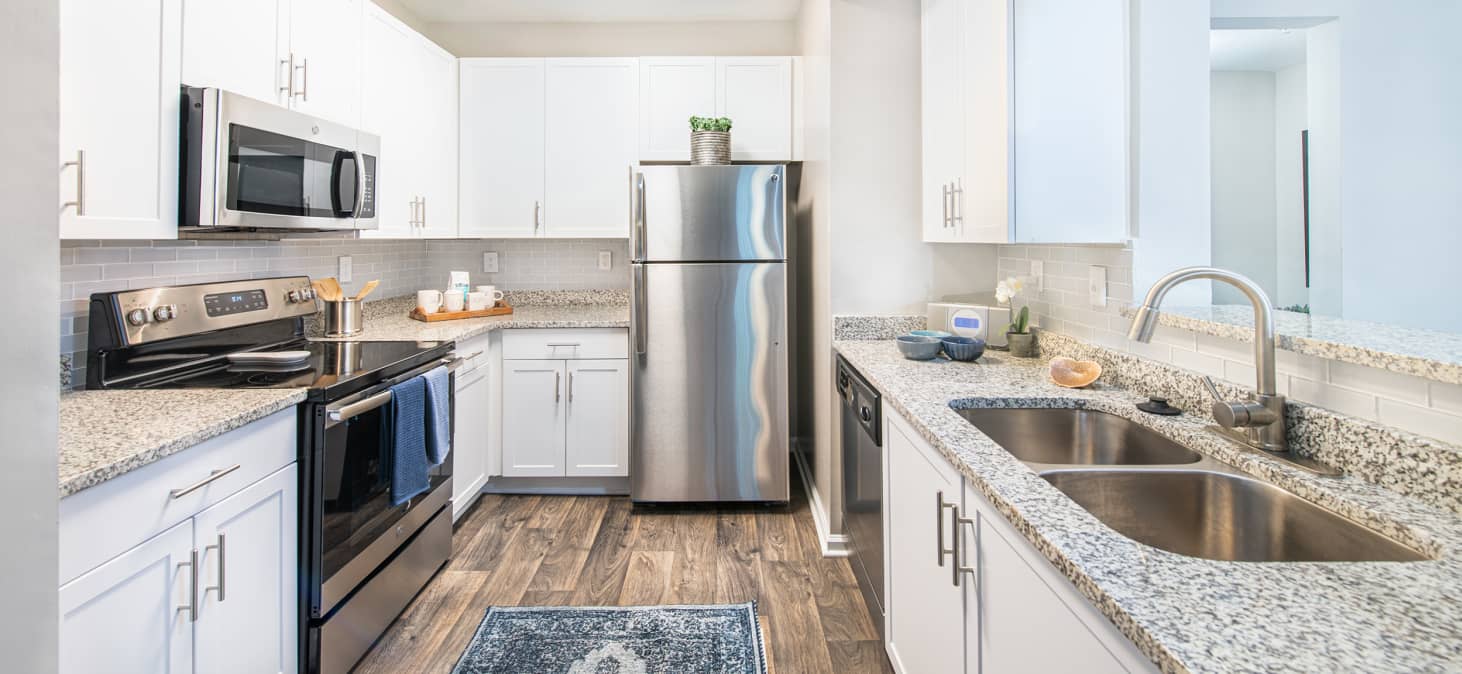 Modern kitchen with white cabinets and stainless steel appliances at MAA Riverside luxury apartments in Atlanta, GA