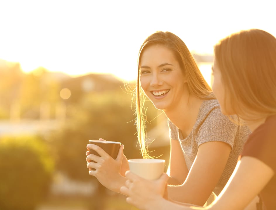 Two women smiling with coffee mugs in their hands