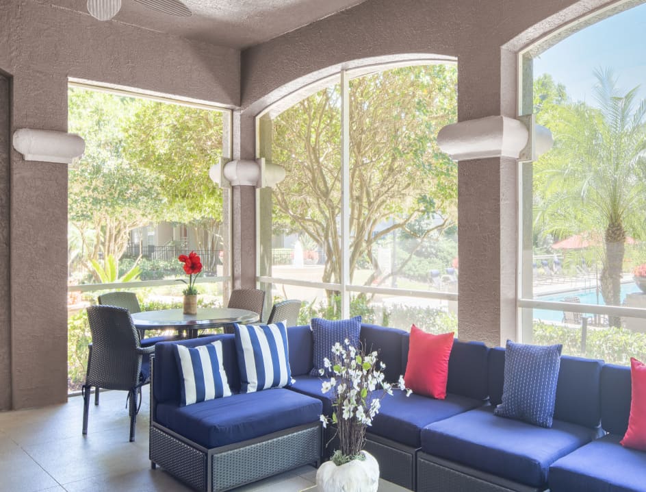 Lounge area with tables and pool view at the Clubhouse Lanai at MAA Heathrow luxury apartments in Orlando, FL