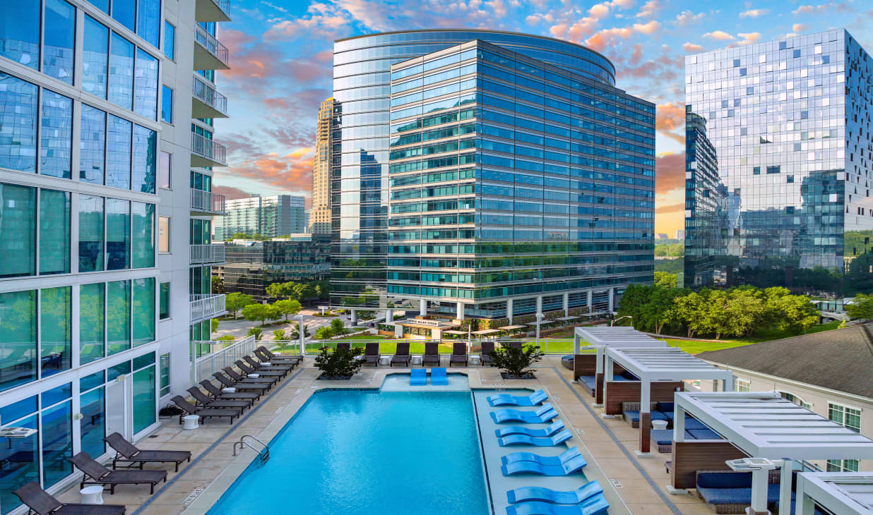 Aerial outward view of rooftop wading pool with sun shelf and skyline view of neighboring high-rise buildings at MAA Lenox luxury apartment homes in Atlanta, GA