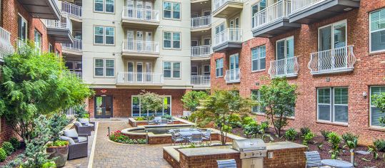 Courtyard with greenery and picnic tables and grill stations at MAA Centennial Park luxury apartments in Atlanta, GA
