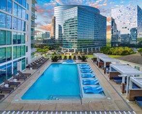 Aerial outward view of rooftop wading pool with sun shelf and skyline view of neighboring high-rise buildings at MAA Lenox luxury apartment homes in Atlanta, GA