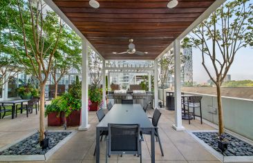 Poolside gated courtyard with outdoor grilling stations, covered patio area with picnic tables, and a view of neighboring high-rise buildings at MAA Lenox luxury apartment homes in Atlanta, GA
