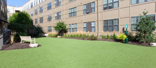 Dedicated dog walk area with artificial turf and benches at Market Station luxury apartments in Kansas City, MO