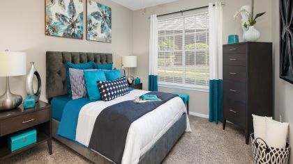 Cozy bedroom with natural light and modern-accented furniture at MAA Heathrow luxury apartments in Orlando, FL