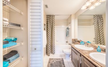 Spacious bathroom with double vanity sink, shower tub with curtains at MAA Heathrow luxury apartments in Orlando, FL