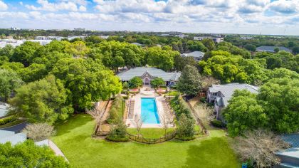 Aerial view of gated pool surrounded by lush green landscapes at MAA Heathrow luxury apartments in Orlando, FL