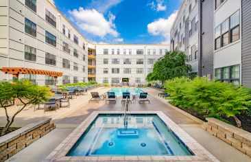 Spacious hot tub spa surrounded by lounge chairs next to the pool at Market Station luxury apartments in Kansas City, MO