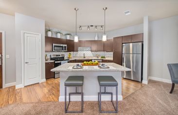 Upscale modern-style kitchen with island and open floorplan dining area at Market Station luxury apartments in Kansas City, MO