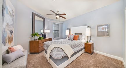 Guest bedroom with wood furniture and ceiling fan at Market Station luxury apartments in Kansas City, MO